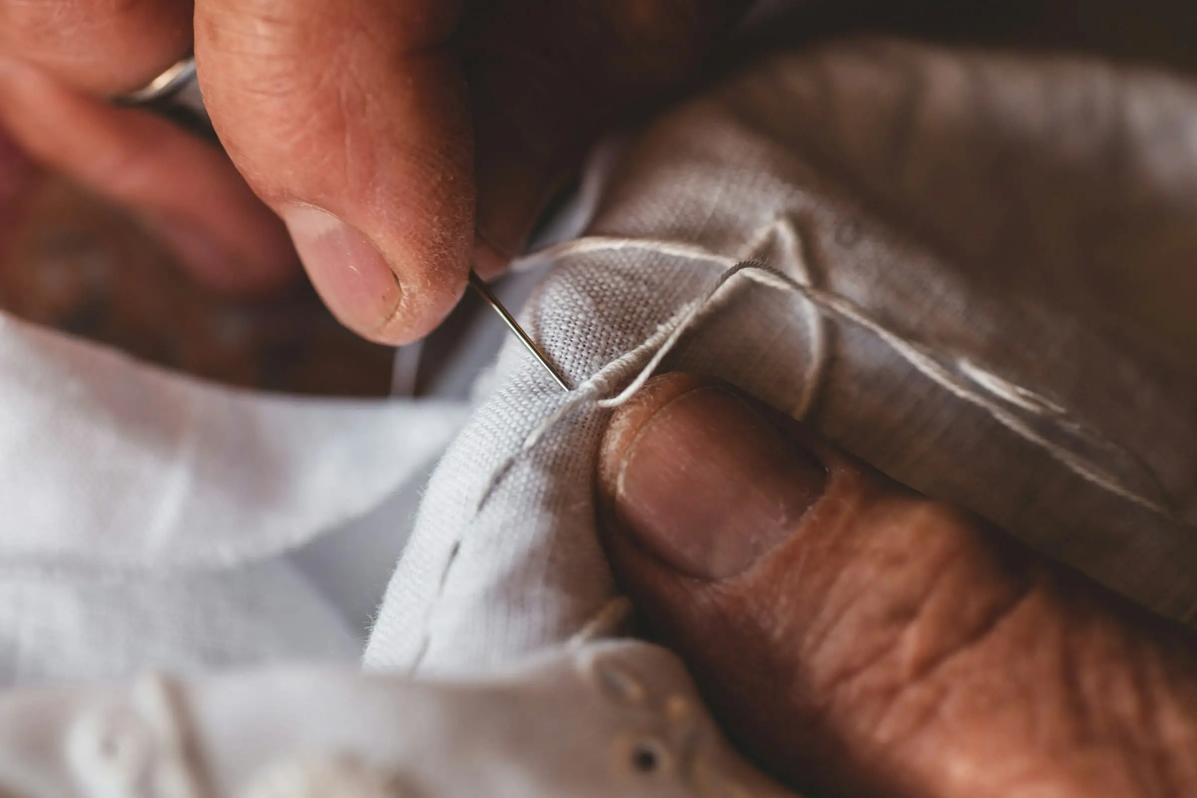 Mains qui cousent un tissu blanc