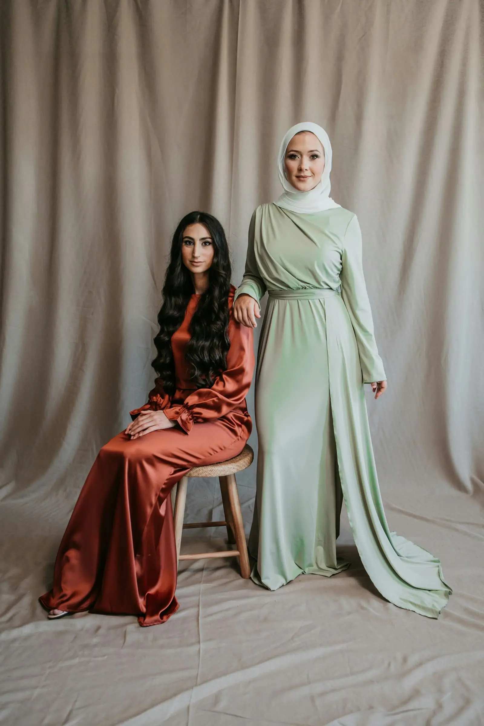 Deux femmes en robes longues de satin rouille et vert sauge